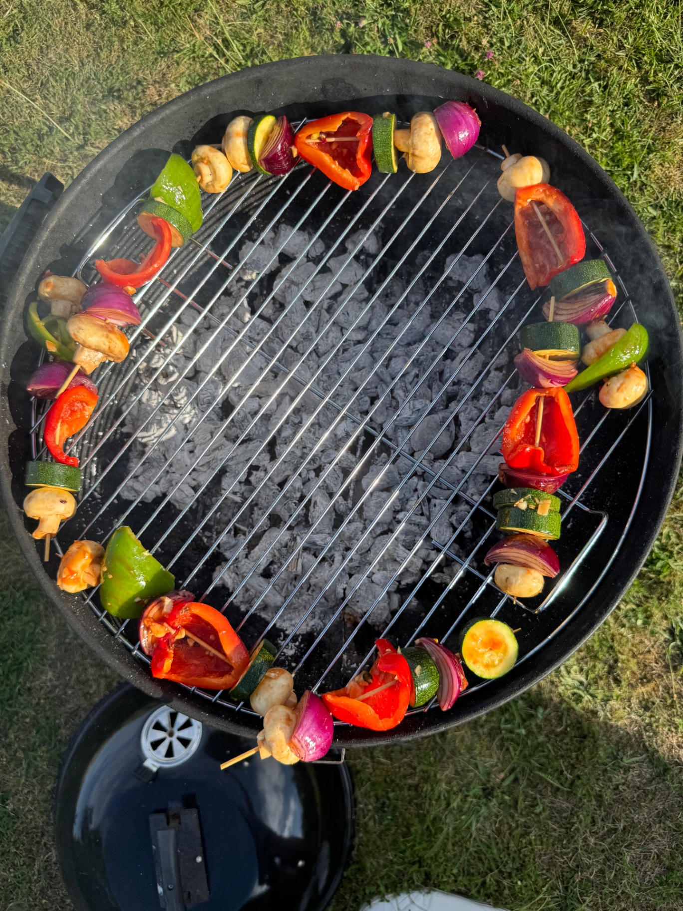 Grönsaksspett som grillas runt kanten på en kolgrill