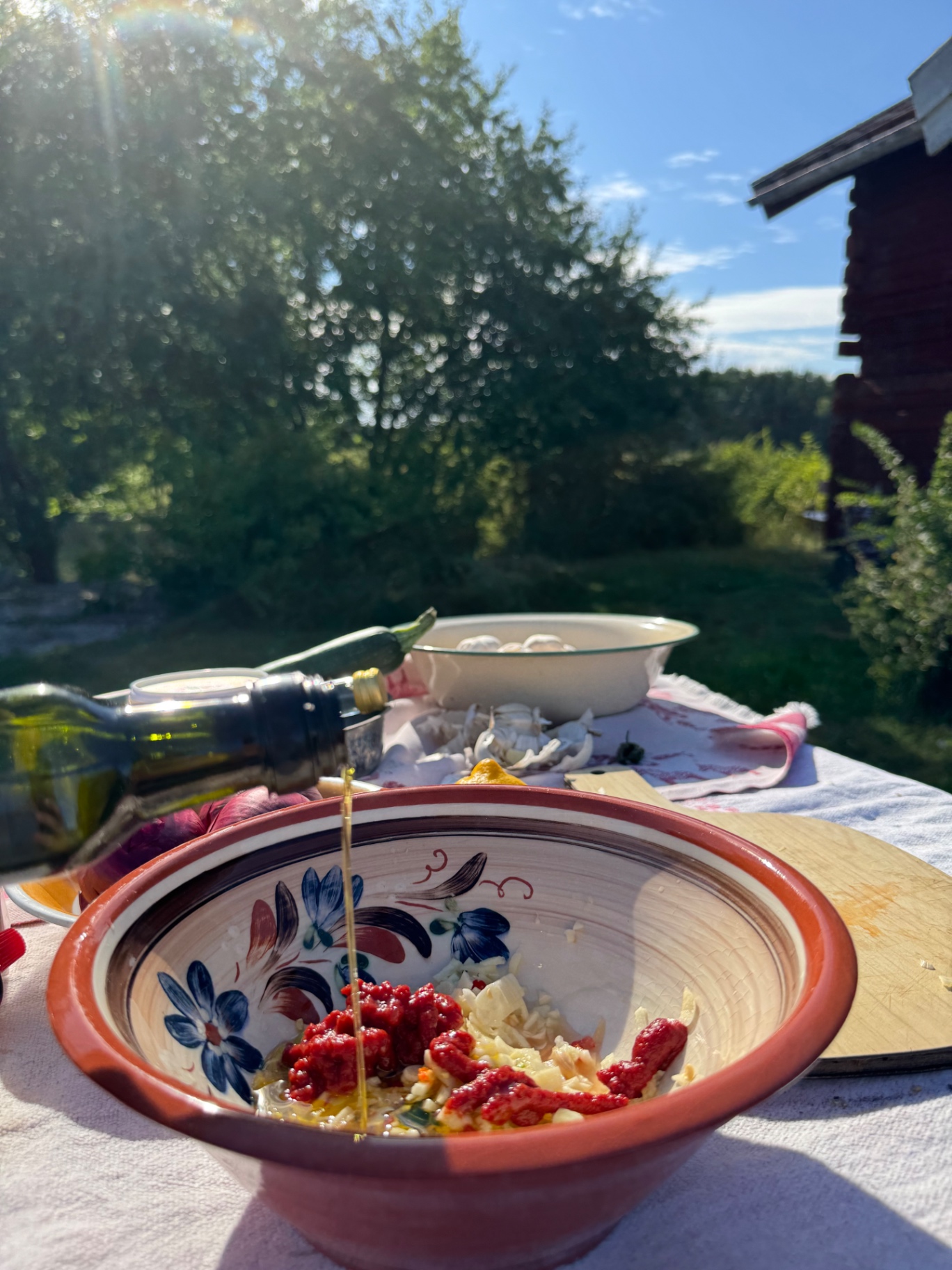 Olivolja hälls över vitlök, chili och tomatpuré i en lerskål