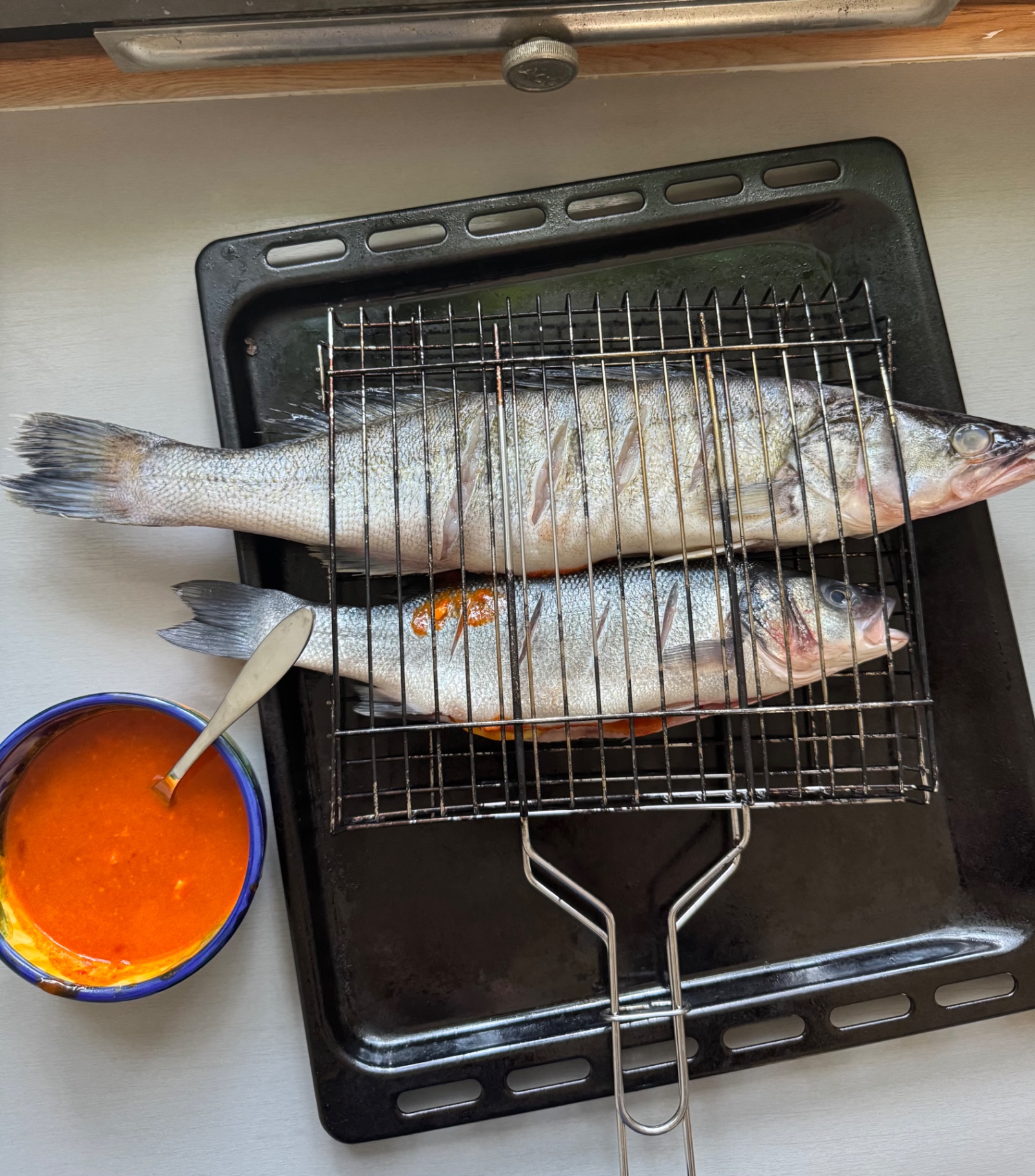 Fiskarna ligger i ett grillgaller för hel fisk på en plåt