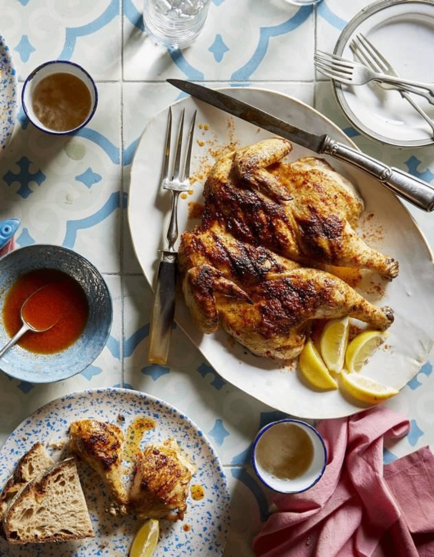 Frango piri-piri uppdukad på fat med citron, sås och bröd på azulejo-kaklat bord