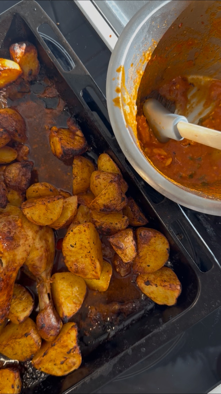 Färdig piri-piri-kyckling med potatis på plåt bredvid en gryta med marinad