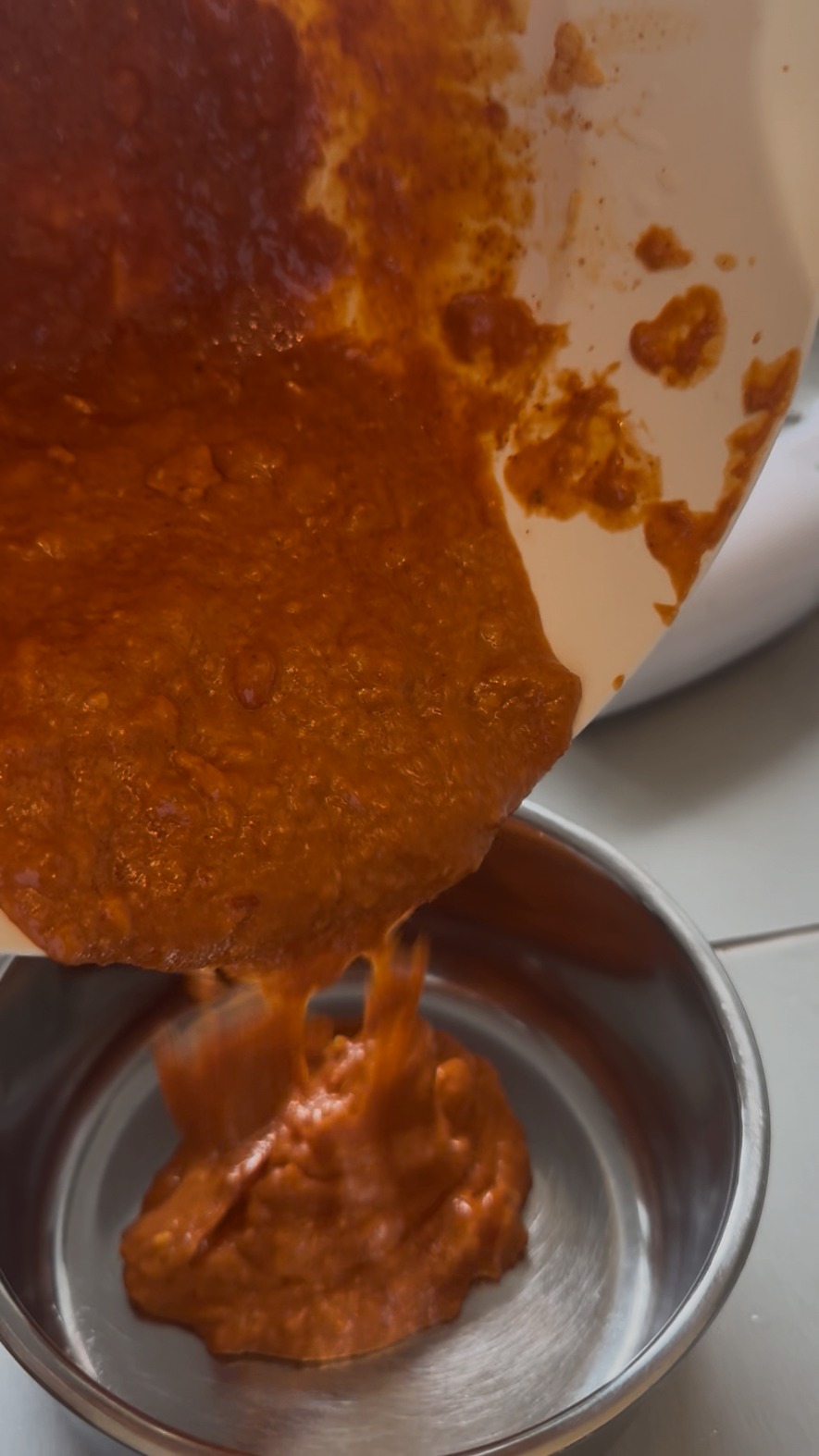 Grov piri-piri-marinad hälls från mixerskålen ner i en stålskål